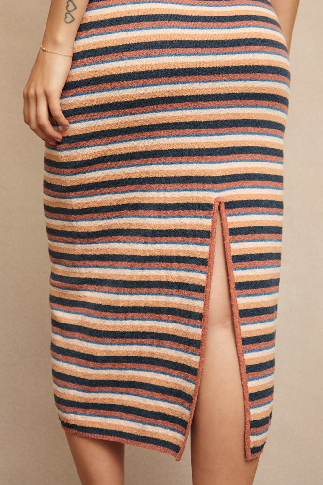 woman wearing a striped knit skirt with a side slit and horizontal stripes in peach, navy, and cream colors
