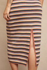 woman wearing a striped knit skirt with a side slit and horizontal stripes in peach, navy, and cream colors