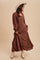 woman wearing a brown long sleeve maxi dress with buttons down the front and a wide-brimmed hat, standing in a flowing pose
