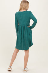 woman wearing a teal ribbed long sleeve dress with a flared skirt and back pleat, paired with white sneakers
