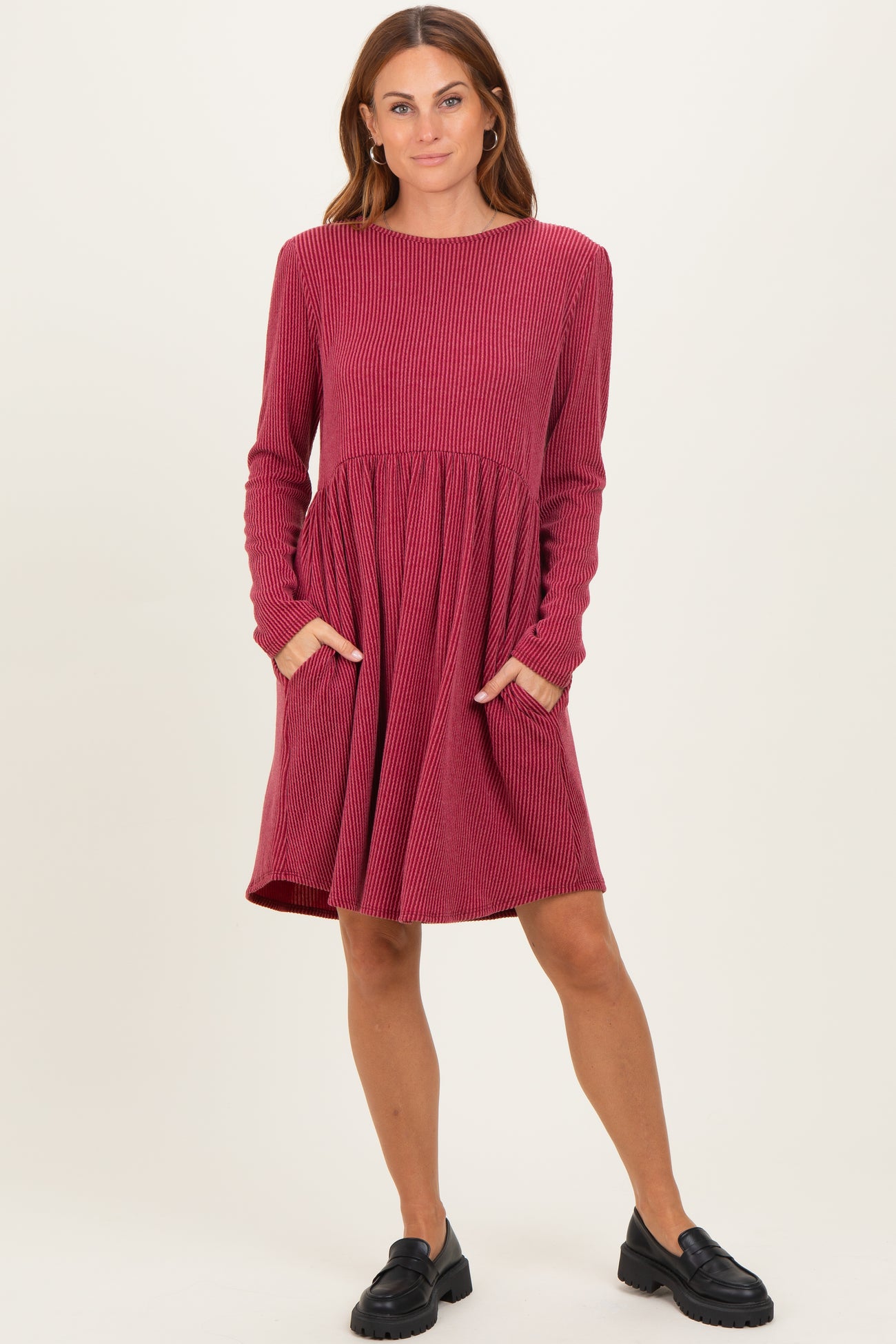 woman wearing a red ribbed long sleeve dress with a fitted bodice and flared skirt, featuring side pockets