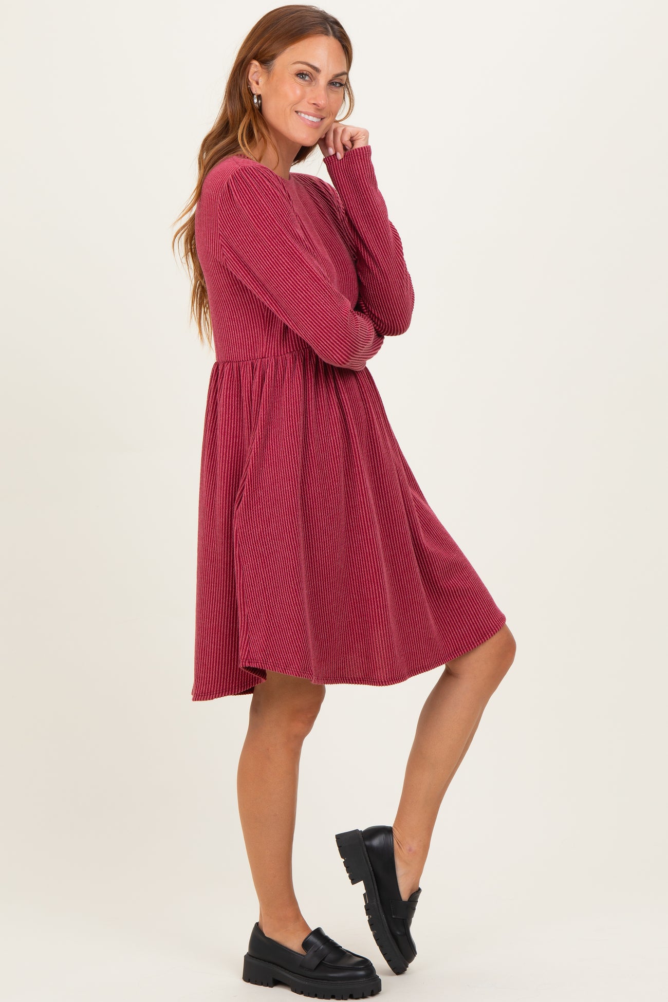 woman wearing a burgundy ribbed long sleeve dress with a flared skirt and black slip-on shoes