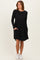 woman wearing a black long sleeve dress with a textured bodice and flared skirt, featuring pockets and paired with white sneakers