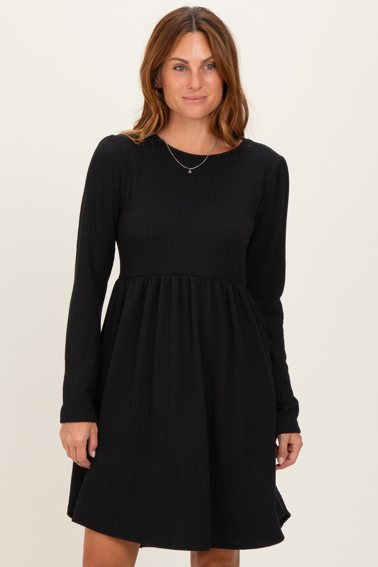 woman wearing a black long sleeve ribbed dress with a flared skirt and round neckline