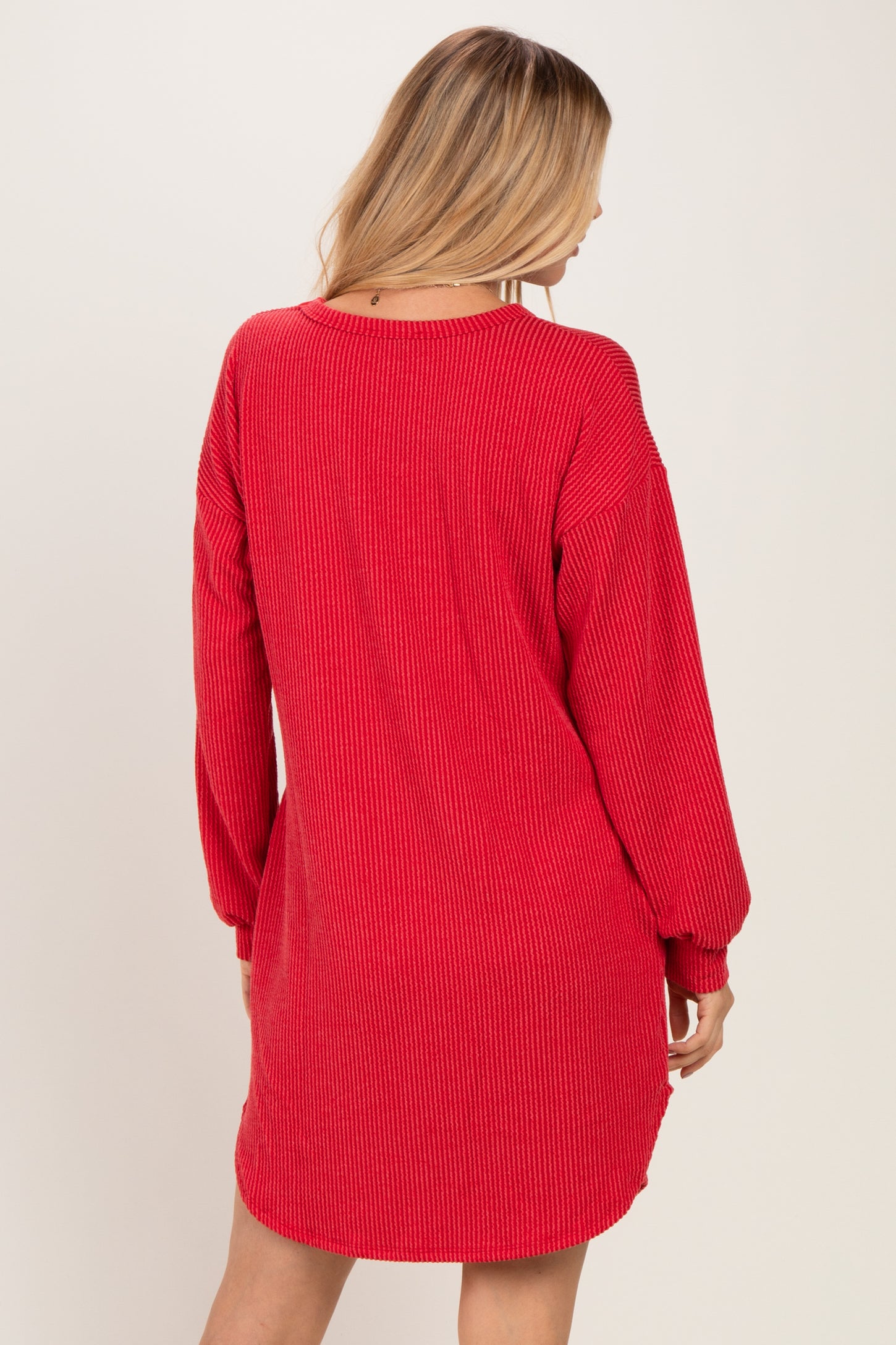 woman wearing a red ribbed long sleeve oversized dress seen from the back