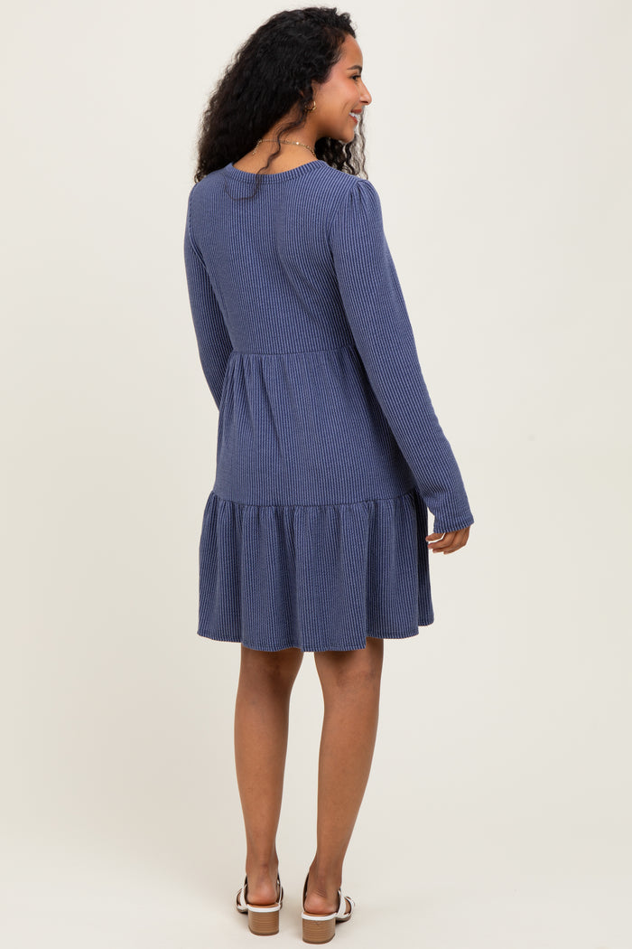 woman wearing a navy blue striped long sleeve maternity dress with a ruffled hem, looking back at the camera