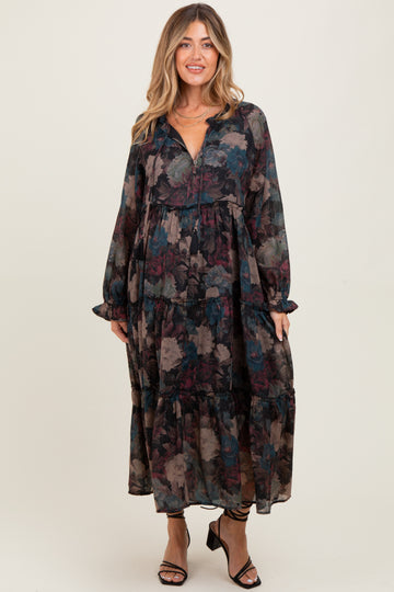 woman wearing a flowy black floral maternity dress with long sleeves and a tiered skirt, holding her baby bump