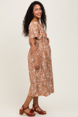 woman wearing a brown floral print maternity dress and showing her baby bump
