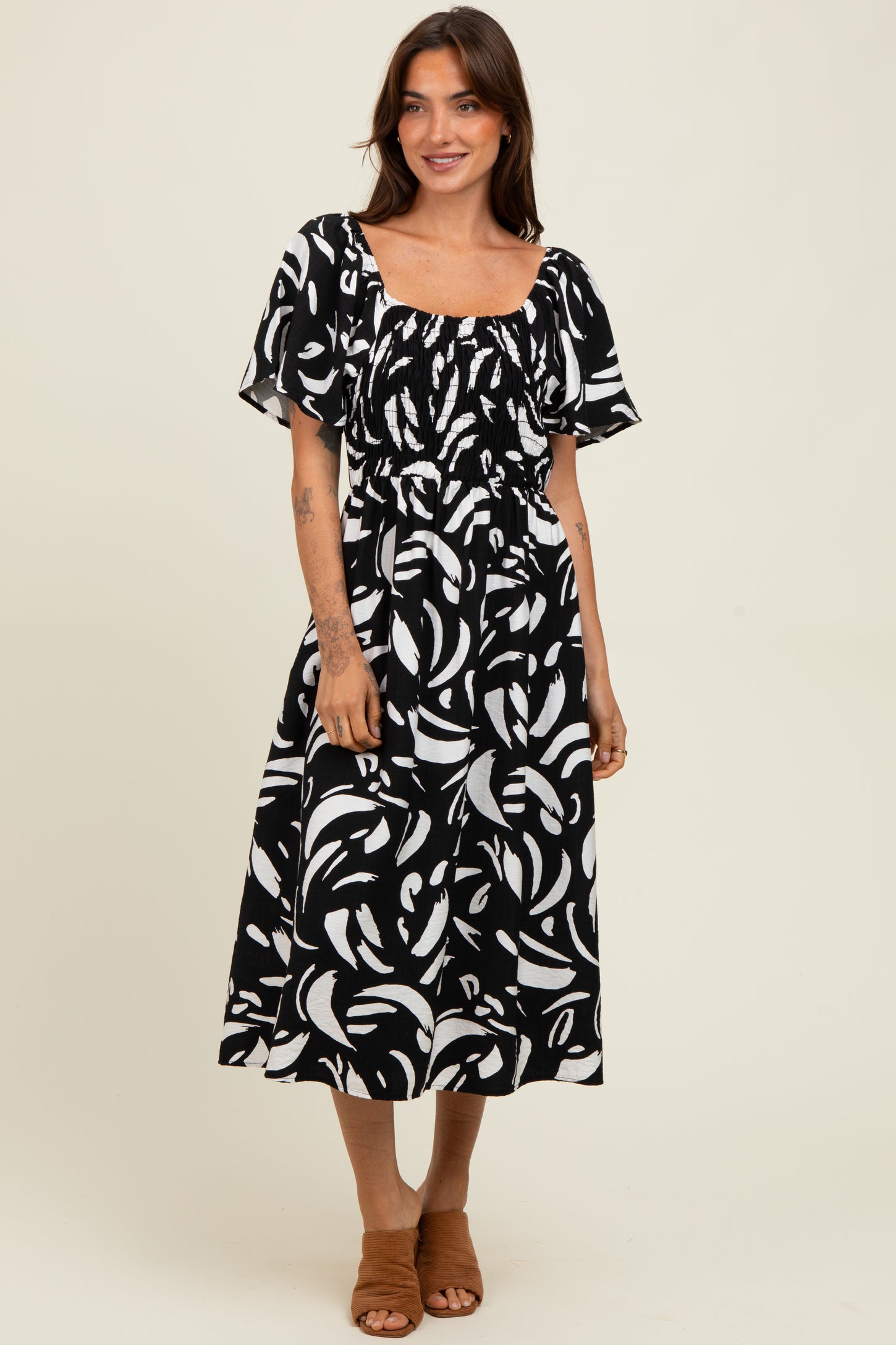 woman wearing a black and white floral print midi dress with a square neckline and short puff sleeves