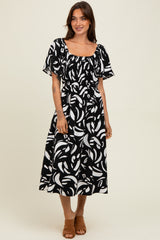 woman wearing a black and white floral print midi dress with a square neckline and short puff sleeves