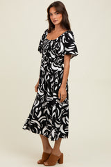woman wearing a black and white printed midi dress with a square neckline and short puff sleeves