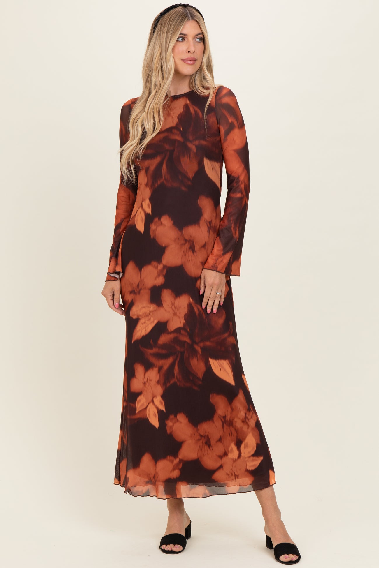 woman wearing a long sleeve dark floral maxi dress with warm tones and a flowy silhouette