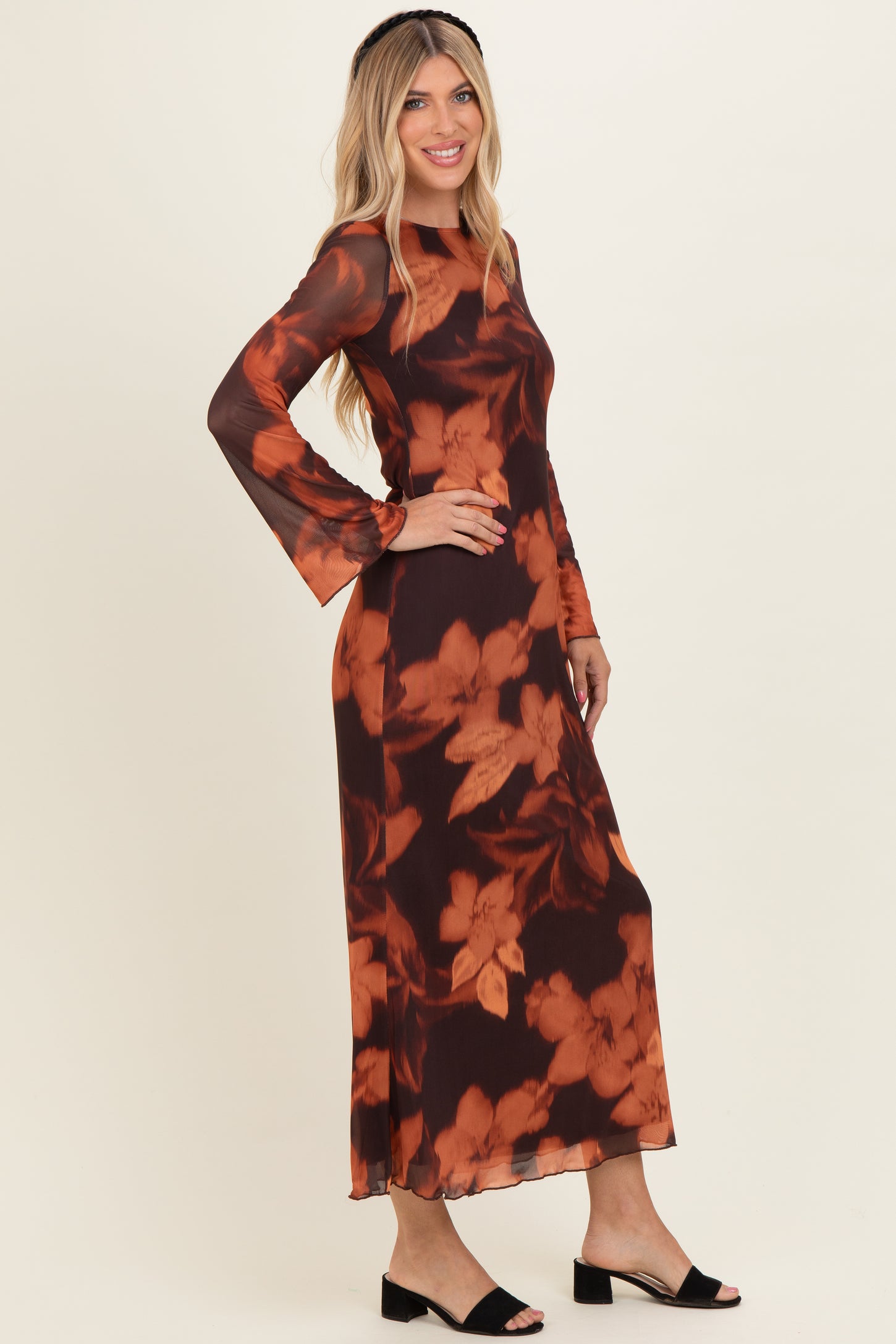 woman wearing a long brown floral maxi dress with bell sleeves and flared hem