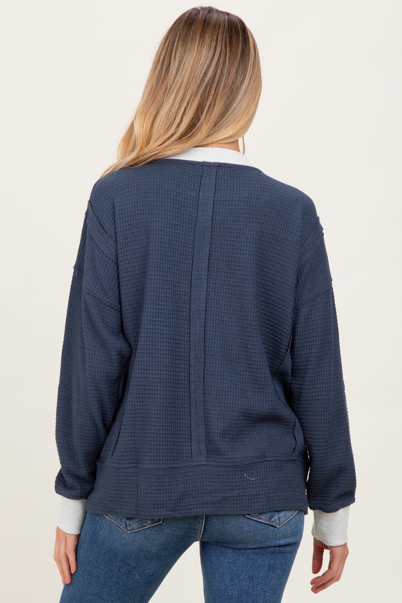 woman wearing a navy blue maternity sweatshirt with a relaxed fit and contrasting cuffs, seen from the back