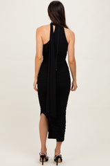 woman wearing a black midi dress with adjustable straps and ruching details, seen from the back