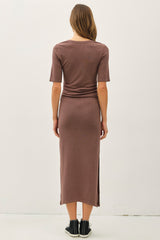 woman wearing a taupe fitted midi dress with short sleeves and side slits, seen from the back