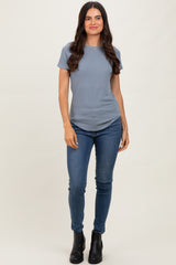 woman wearing a light blue short sleeve top and dark skinny jeans, paired with black ankle boots