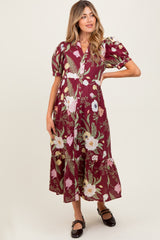 woman wearing a burgundy floral maternity dress with puff sleeves and a tiered hem