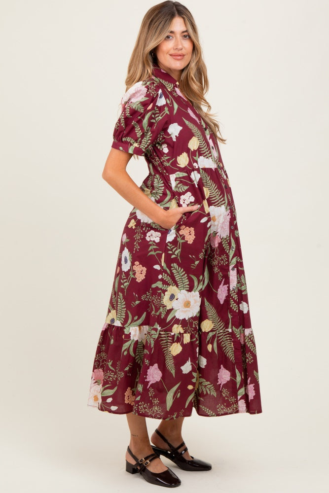 woman wearing a burgundy floral maternity dress with short sleeves and a tiered skirt, showcasing her baby bump