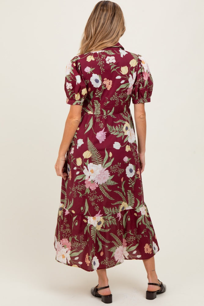 woman wearing a burgundy floral maternity maxi dress with puff sleeves and a tiered hem, showing a visible baby bump