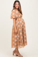 woman wearing a tan floral maternity dress with puff sleeves and a visible baby bump