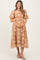 woman wearing a tan floral maternity dress with puff sleeves and holding her baby bump