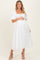 woman wearing a white floral maternity dress with puff sleeves and a fitted bodice, gently holding her baby bump