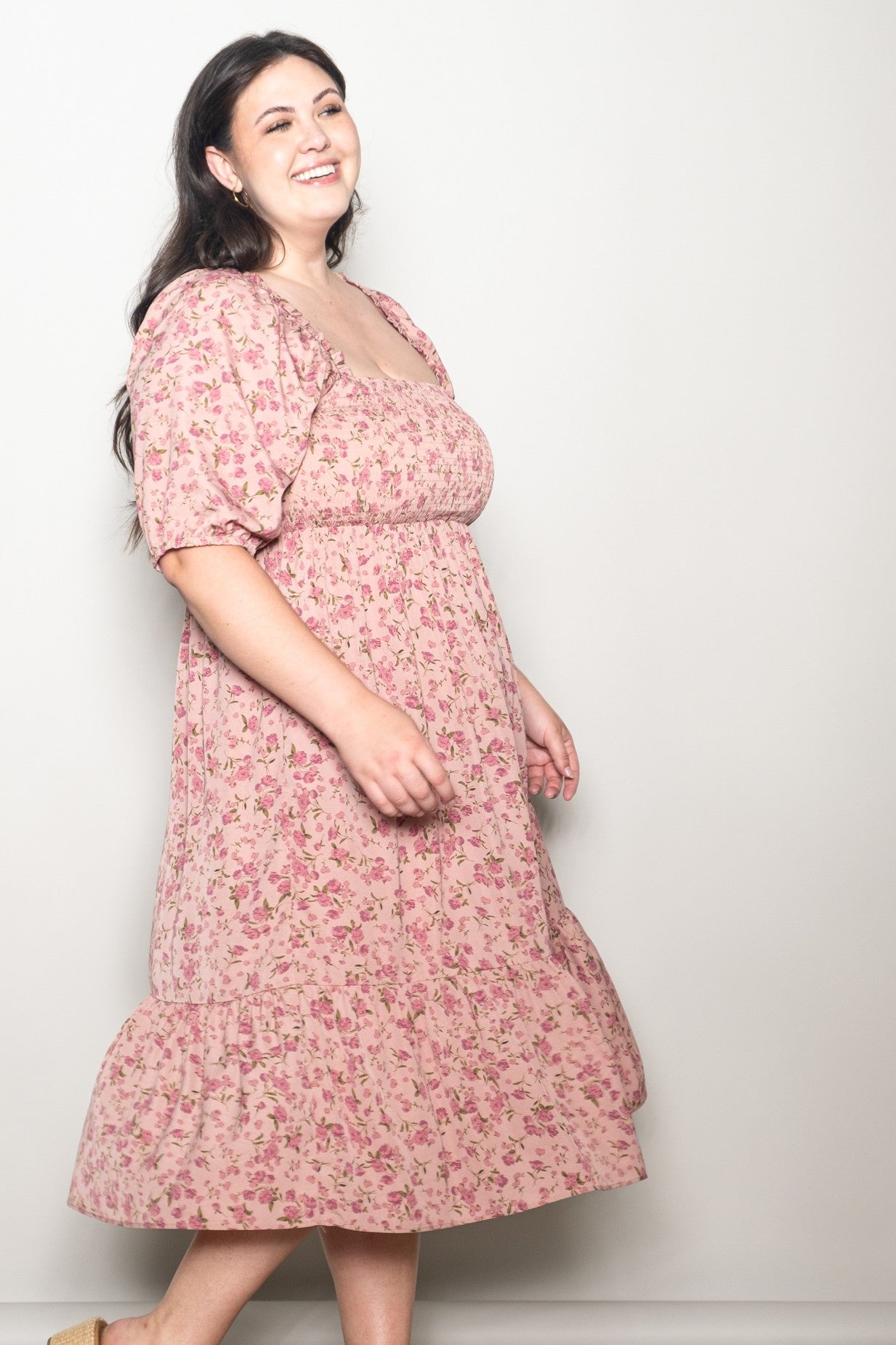 woman wearing a pink floral plus-size midi dress with puff sleeves and a tiered skirt