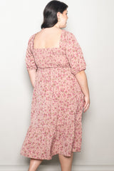 woman wearing a pink floral plus-size midi dress with short puff sleeves and a gathered waist, photographed from the back