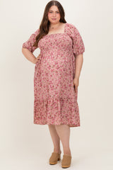 woman wearing a pink floral maternity dress with puff sleeves and a tiered hem, showcasing her baby bump