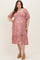 woman wearing a pink floral maternity dress with puff sleeves and a tiered hem, showcasing her baby bump