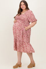 woman wearing a pink floral maternity dress with puff sleeves and pockets, showing her baby bump