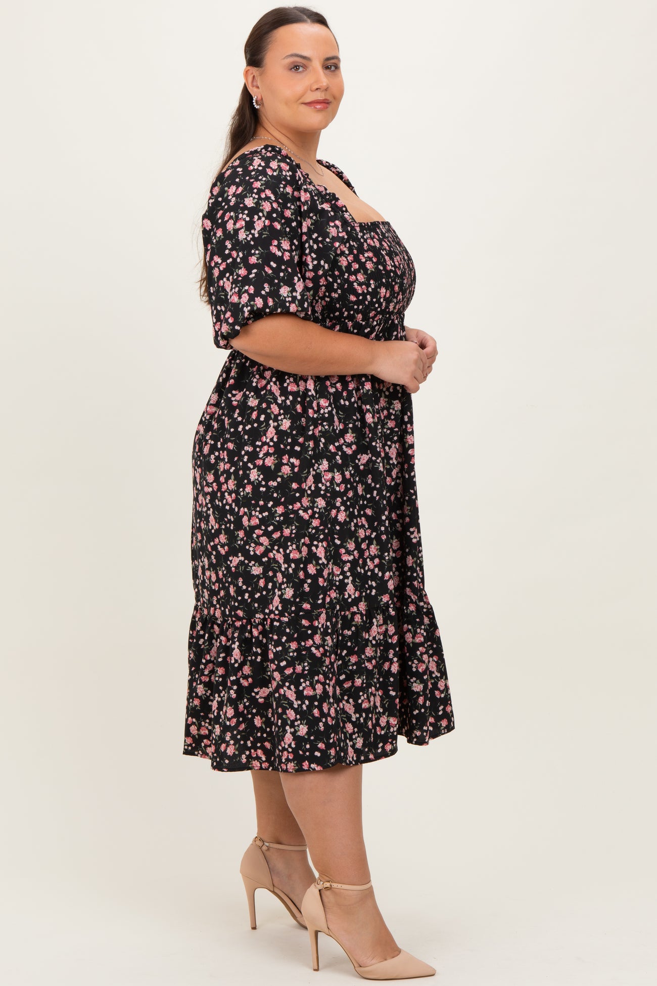 woman wearing a black floral plus-size midi dress with short sleeves and a ruffled hem