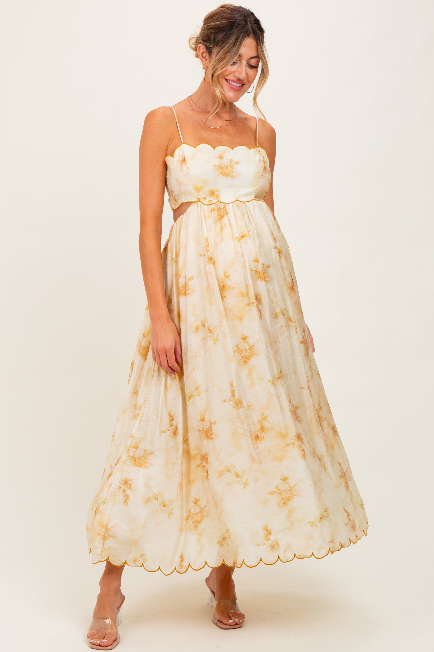 woman wearing a floral-patterned maternity maxi dress with scalloped edges and a baby bump visible