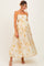 woman wearing a floral-patterned maternity maxi dress with scalloped edges and a baby bump visible
