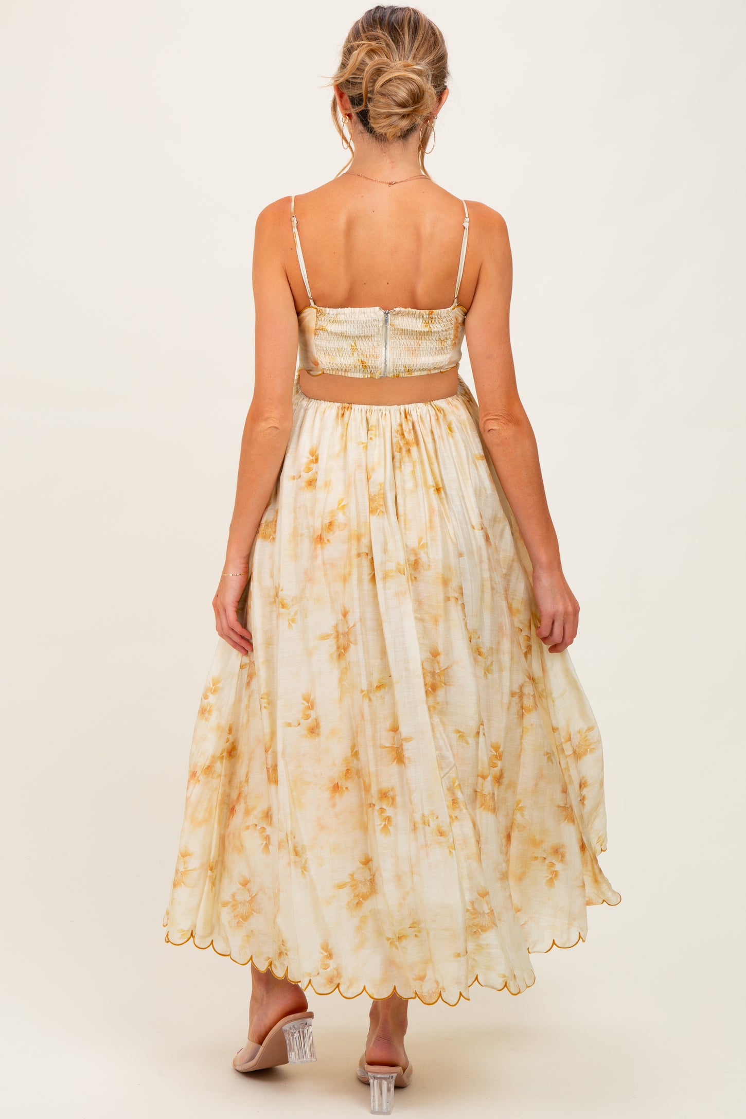 woman wearing a floral print maternity dress with a smocked bodice and a flowy skirt, showing a baby bump from behind