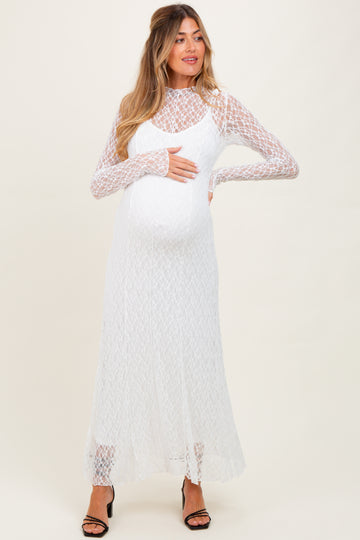 woman wearing a white lace long sleeve maternity dress and holding her baby bump