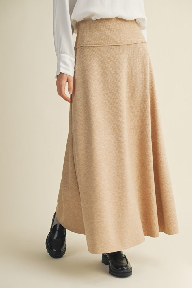 woman wearing a beige maxi skirt with a flared silhouette and paired with black ankle boots