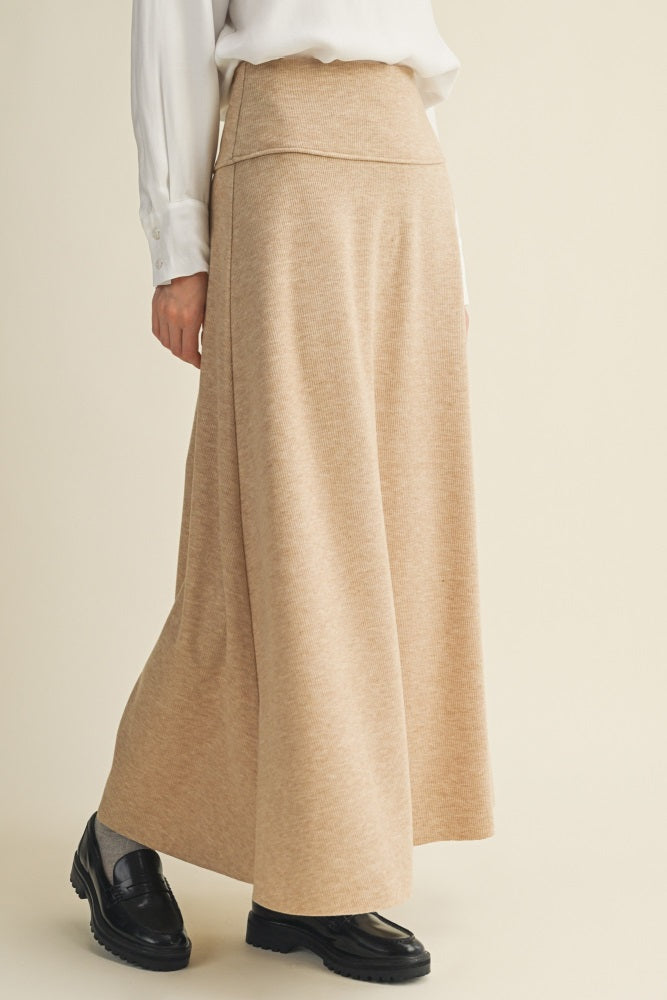 woman wearing a cream-colored maxi skirt with a wide waistband and a flowy silhouette