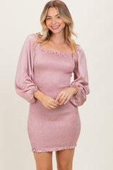 woman wearing a light pink smocked mini dress with puff sleeves and ruffle trim