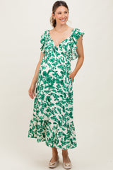 woman wearing a green floral maternity dress with ruffled sleeves and a tiered hem, showing her baby bump