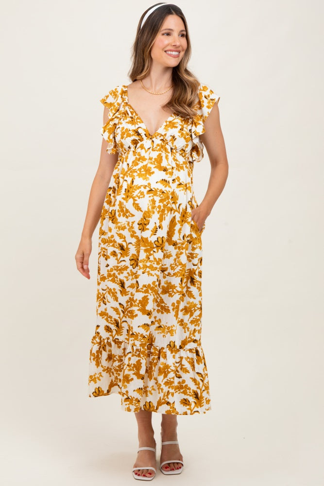 woman wearing a yellow and white floral print maternity dress with ruffle sleeves and a tiered skirt, holding her baby bump
