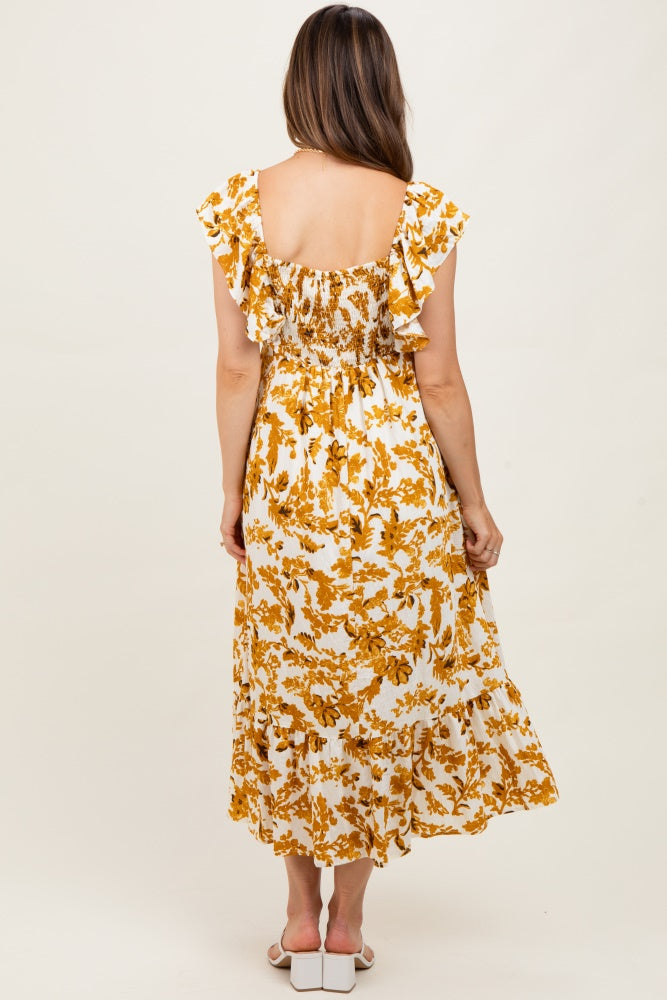 woman wearing a yellow floral print maternity dress with ruffled sleeves and a smocked back, showing her baby bump.