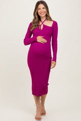 woman wearing a fuchsia long sleeve maternity bodycon dress with a cutout detail and holding her baby bump