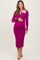 woman wearing a fuchsia long sleeve maternity bodycon dress with a cutout detail and holding her baby bump
