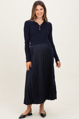 woman wearing a navy blue maternity dress with a collared neck and pleated skirt, showcasing her baby bump.