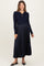 woman wearing a navy blue maternity dress with a collared neck and pleated skirt, showcasing her baby bump.