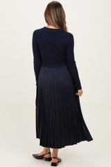 woman wearing a navy blue long sleeve maternity dress with a pleated skirt, showing her back and no visible baby bump