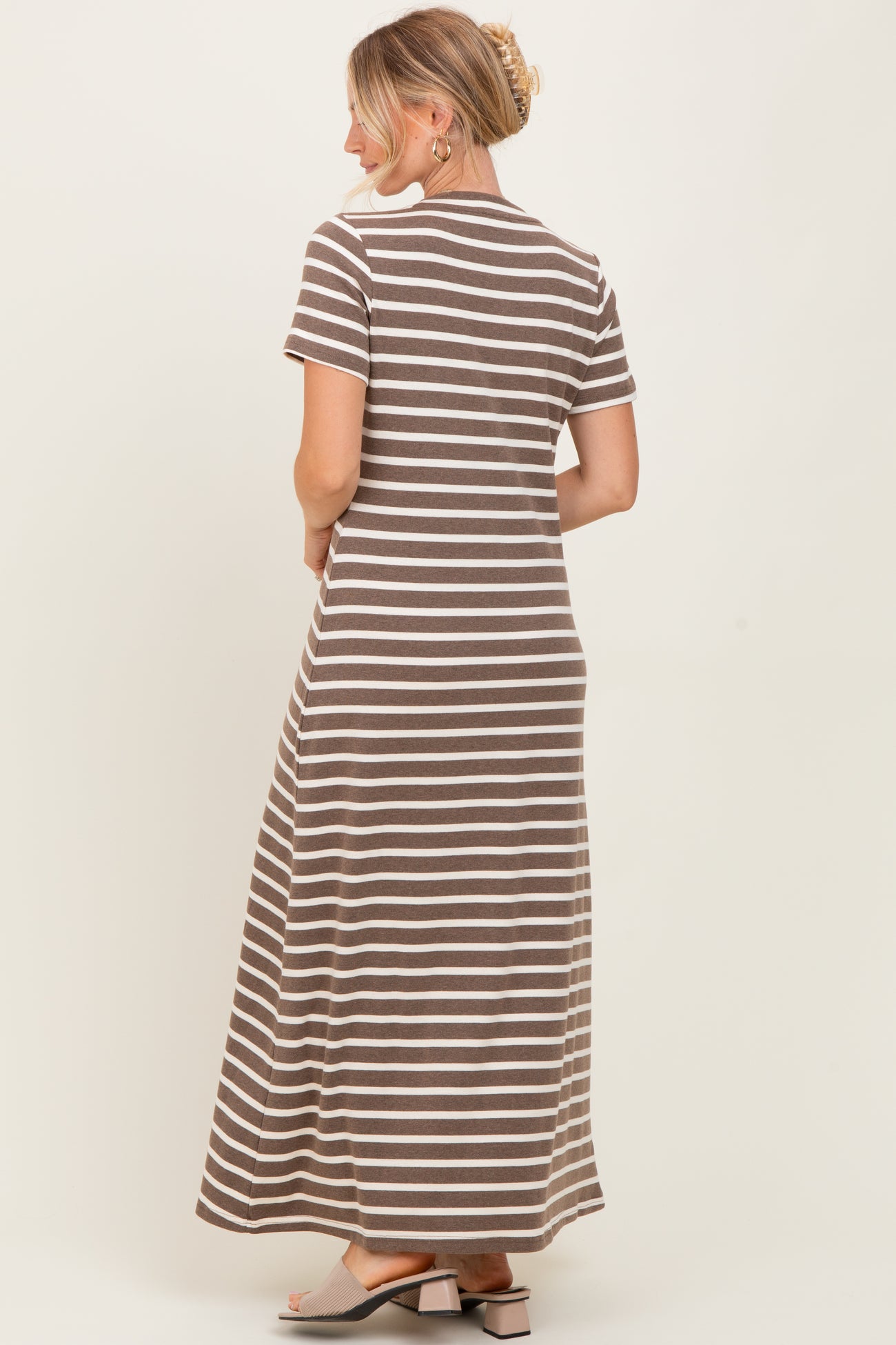 woman wearing a brown and white striped maxi dress with short sleeves, viewed from the back