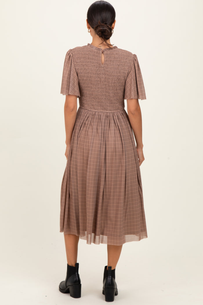 woman wearing a brown checkered midi dress with short puff sleeves and a smocked back detail